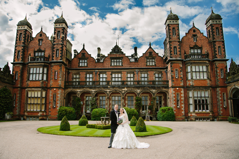 Bride and Groom standing in front of the grand main hall at Capethorne