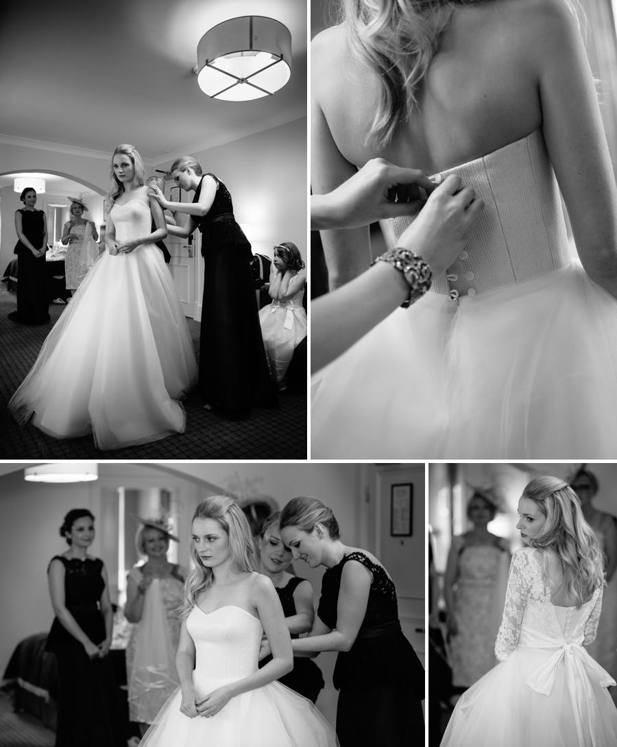 Bride getting into her wedding dress helped by the bridesmaids