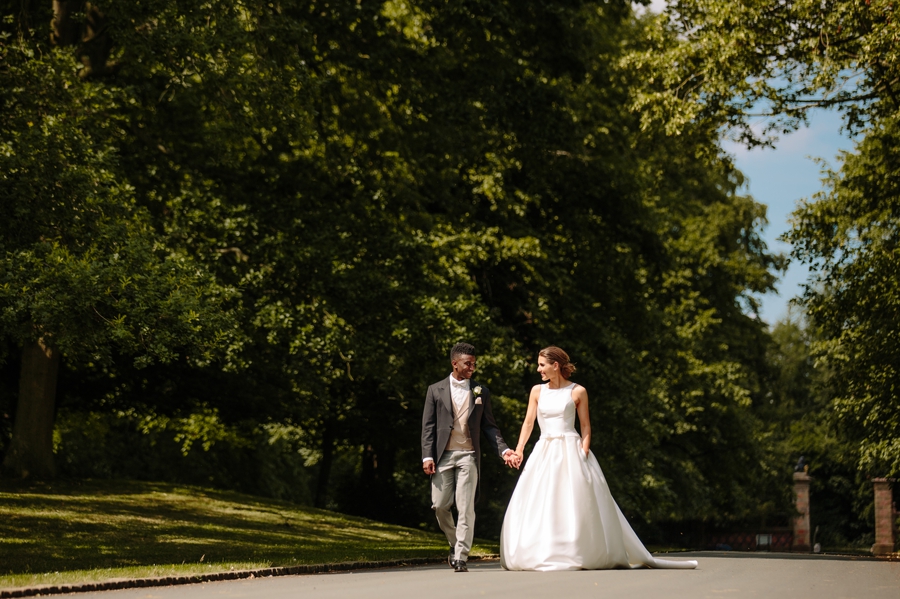 Bride and groom walking hand in hand down the driveway at Dorfold Hall