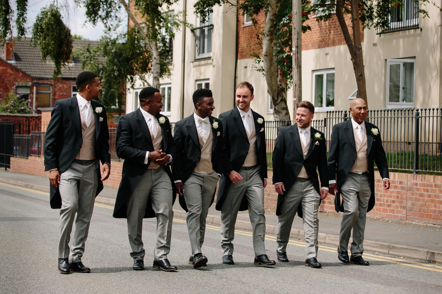 The groom and groomsmen walking to the church