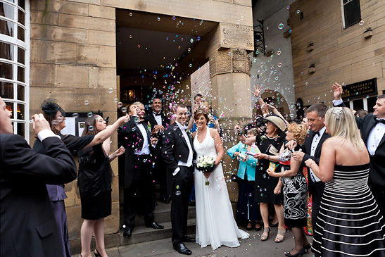 Guests blow bubbles over Bride and Groom