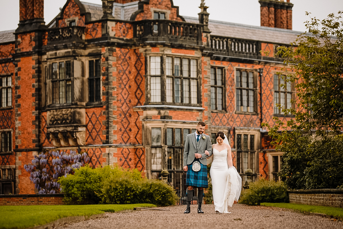 Bride and Groom photographed walking in the gardens in front of Arley Hall