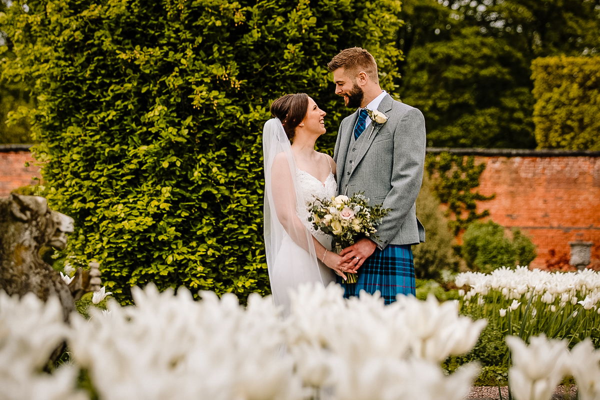 Bride and Groom in the gardens amongst the flowers at Arely Hall