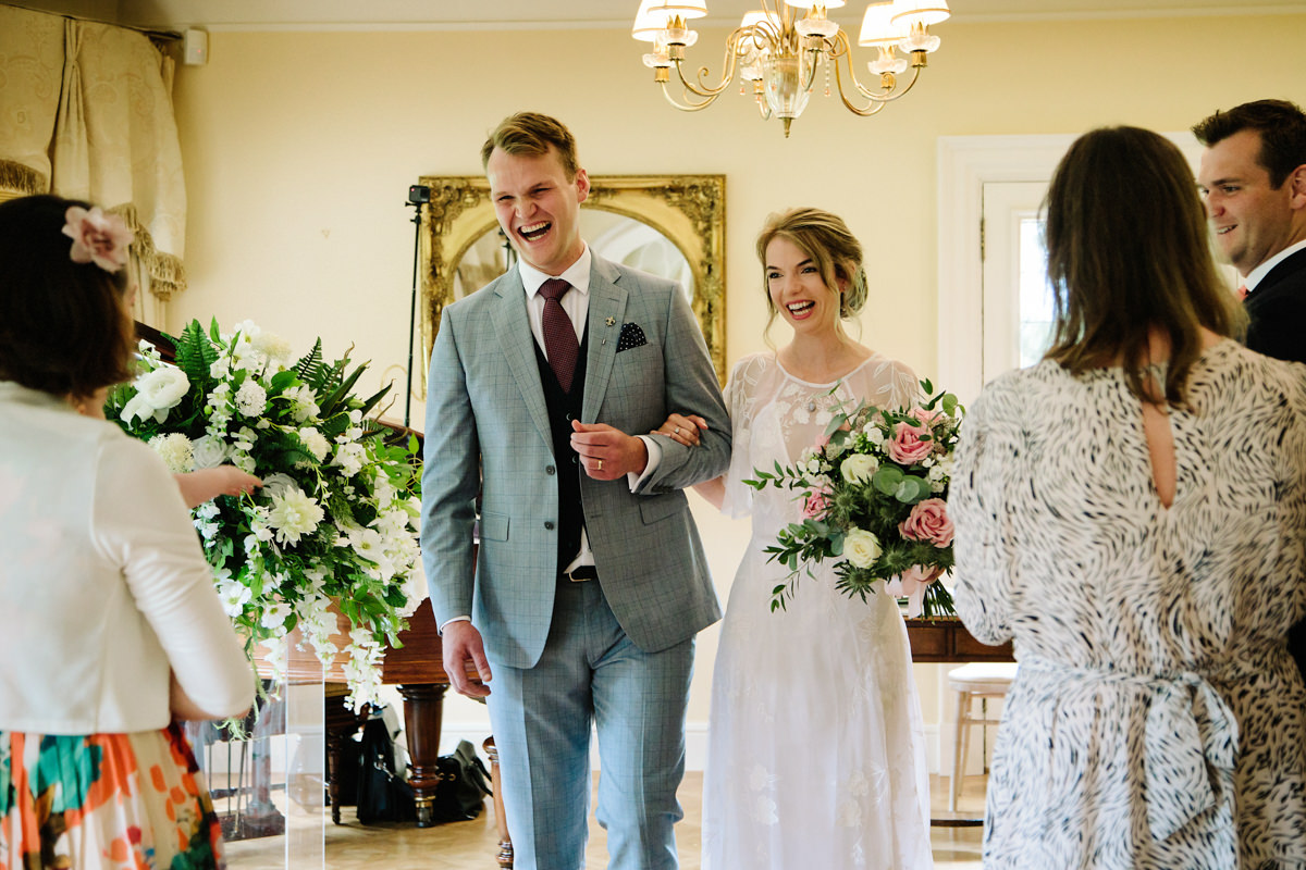 Bride and Groom walking sown the aisle in the piano room at Colshaw Hall