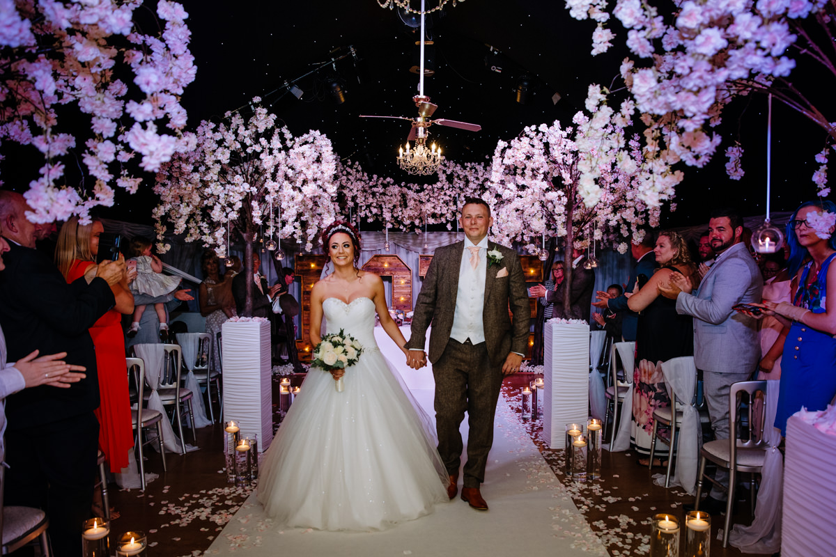Bride and Groom walking down the aisle under the stars at Heaton House Farm