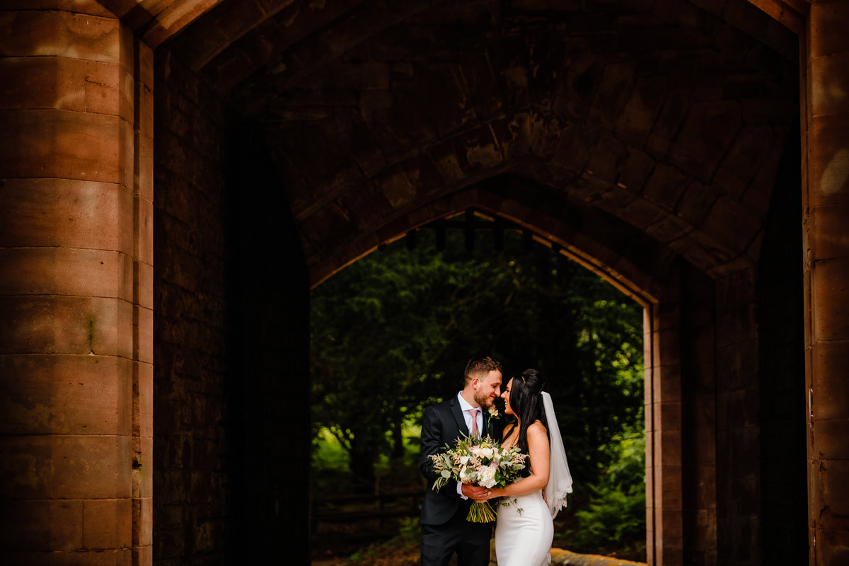 Bride and Groom in love holding each other near the drawbridge at Peckforton Castle