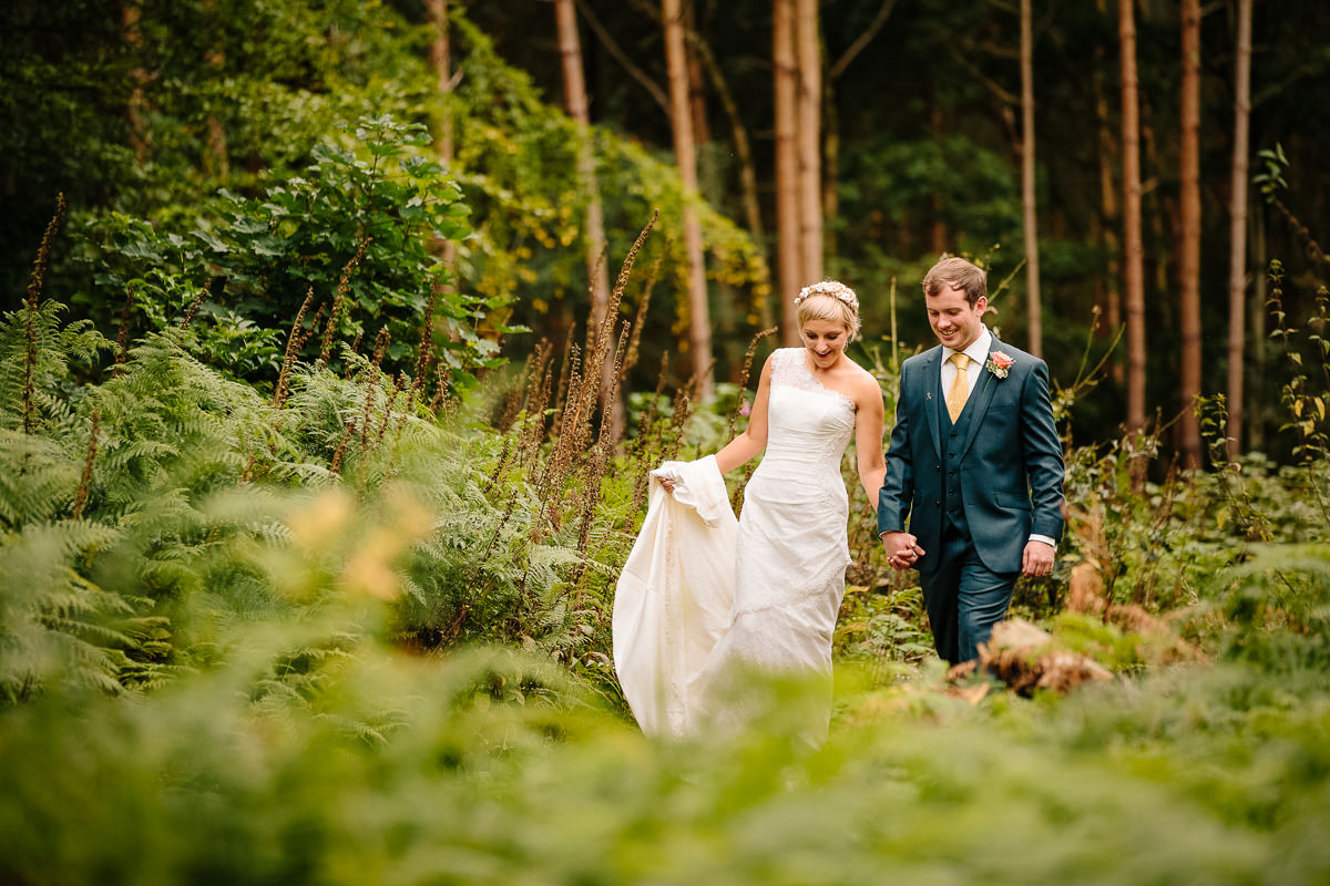 Bride and Groom walking together in the grounds of Peckforton Castle woods