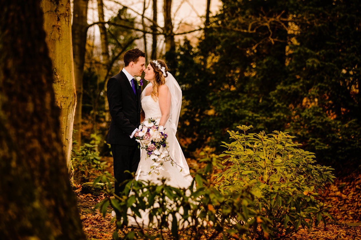 Bride and groom together in love in the woods at Peckforton Castle