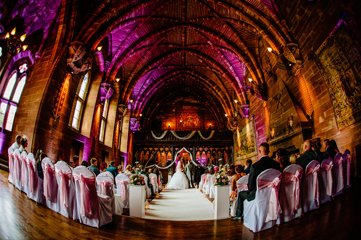 The Great Hall at Peckforton Castle during a ceremony with purple uplighters