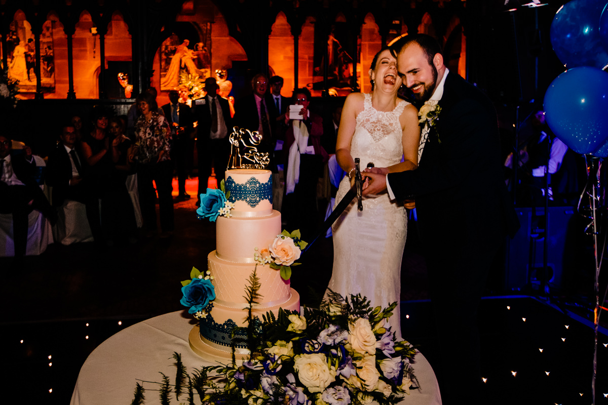 Bride and groom cutting the cake with a sword at Peckforton Castle