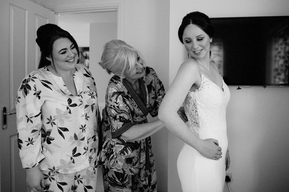 Mother of the bride helping bride into her wedding dress