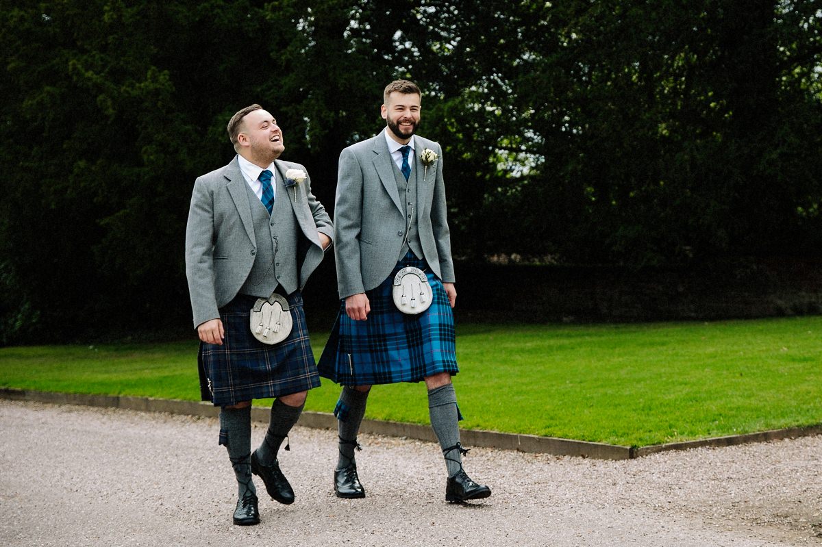 Groom and his best man in kilts laughing together