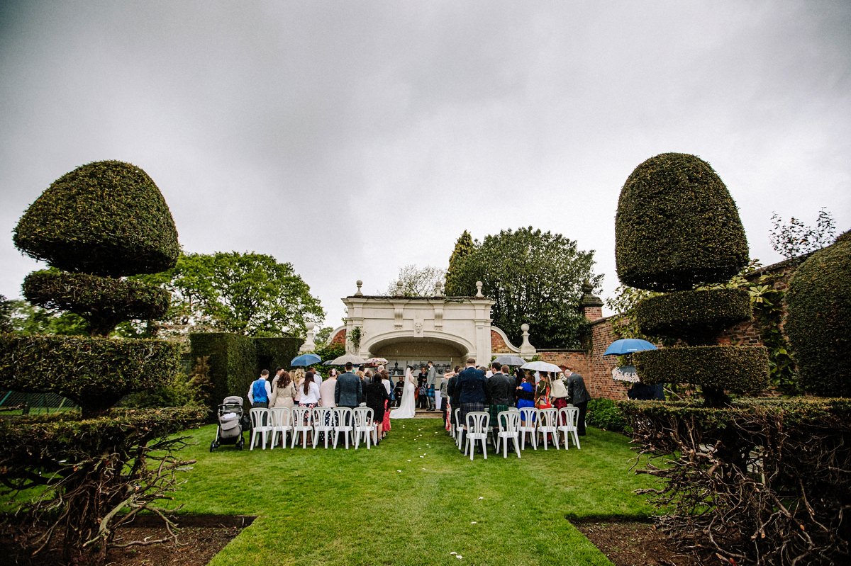 Overview of the alcove and wedding guests for the outdoor wedding ceremony at Arley Hall