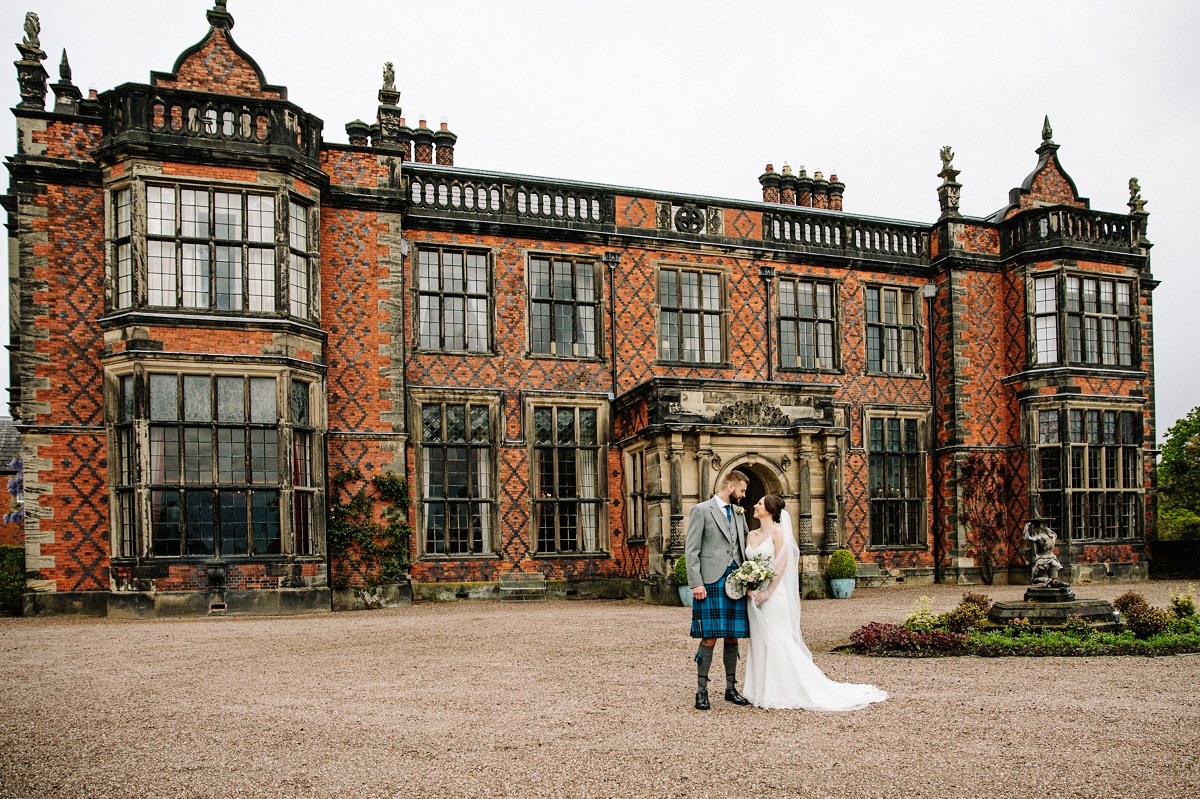 Bride and groom in front of the grand elegant Arley Hall