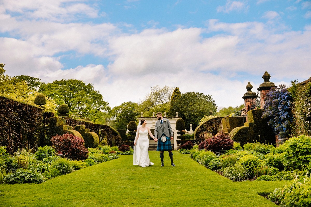 Bride and Groom walking hand in hand in the gorgeous gardens at Arley Hall