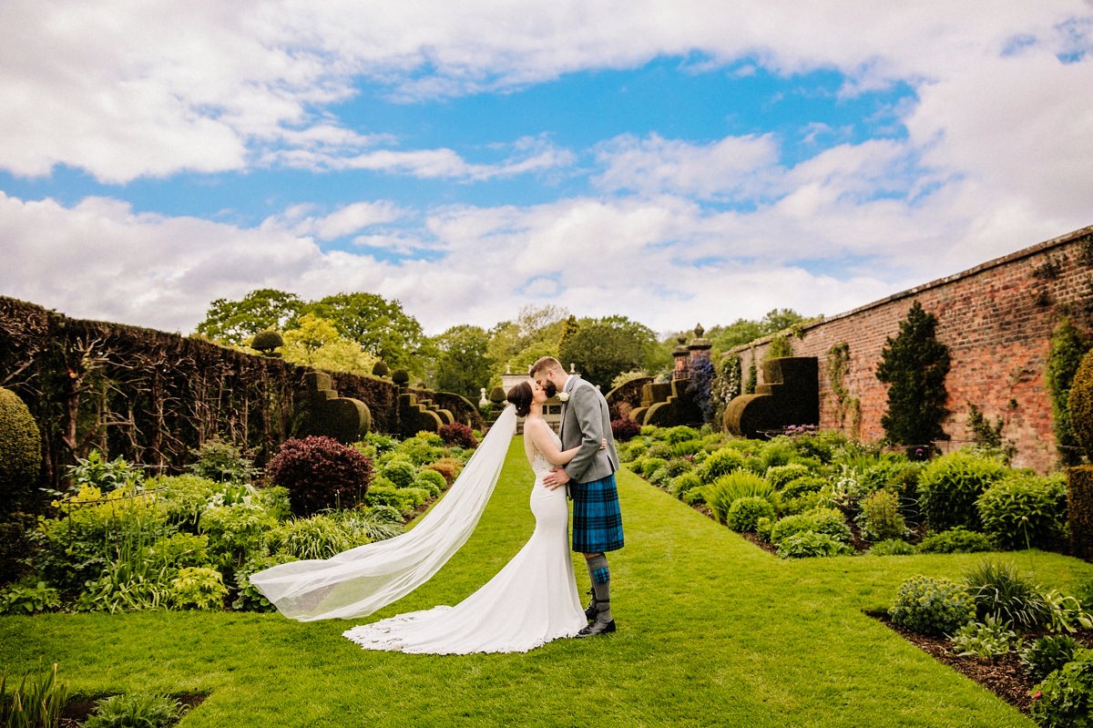 Bride with her wedding veil blowing in the wind with Arley Hall gardens