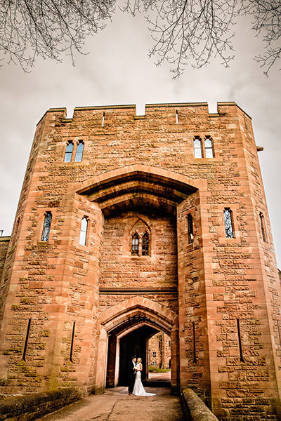 Bride and groom in front of the drawbridge at Peckforton Castle