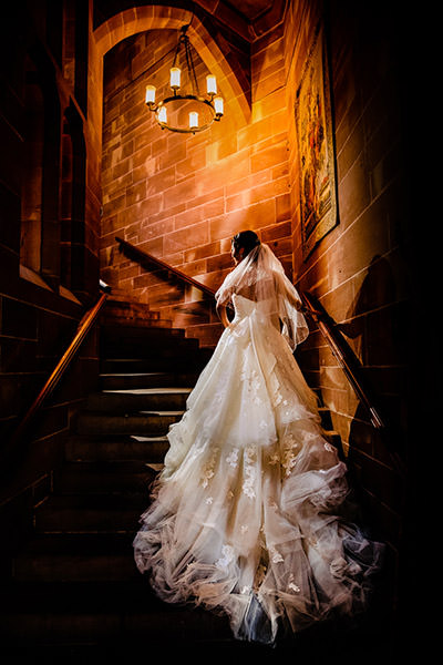 The gorgeous staircase at Peckforton castle with the back of the brides wedding dress