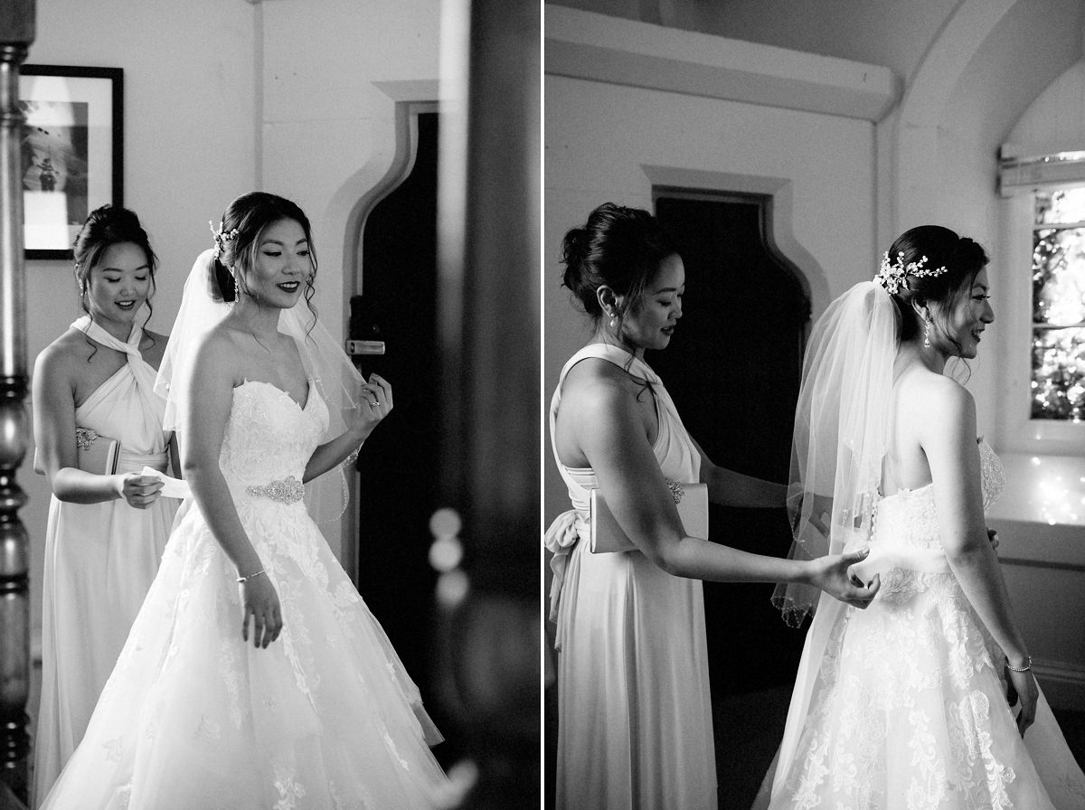 Brides sister helping her in her wedding dress 