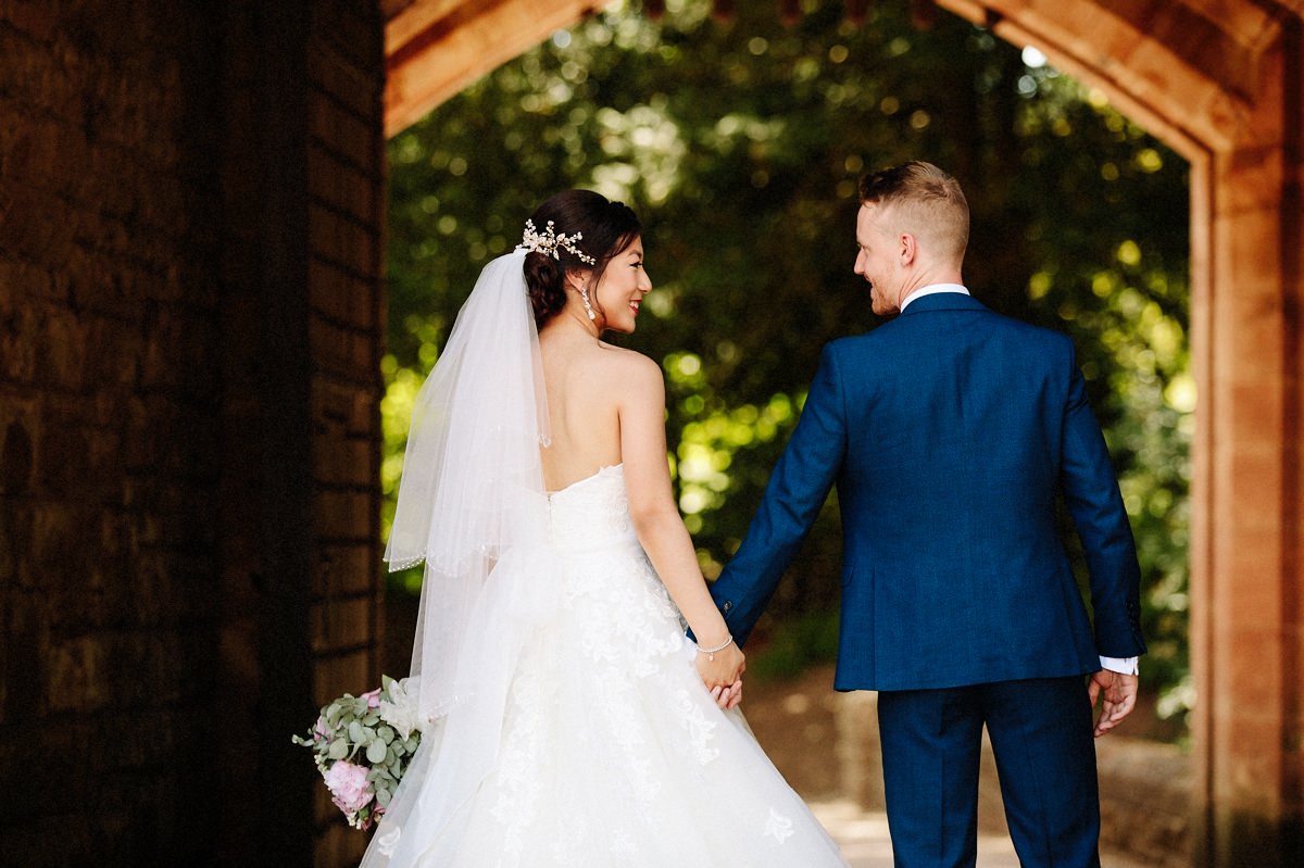 Gorgeous bride with her new husband holding hands at Peckforton Castle