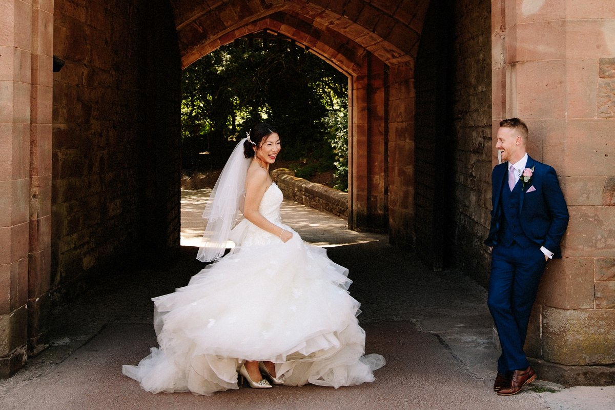 Bride swishing her wedding dress and having fun while her groom looks on