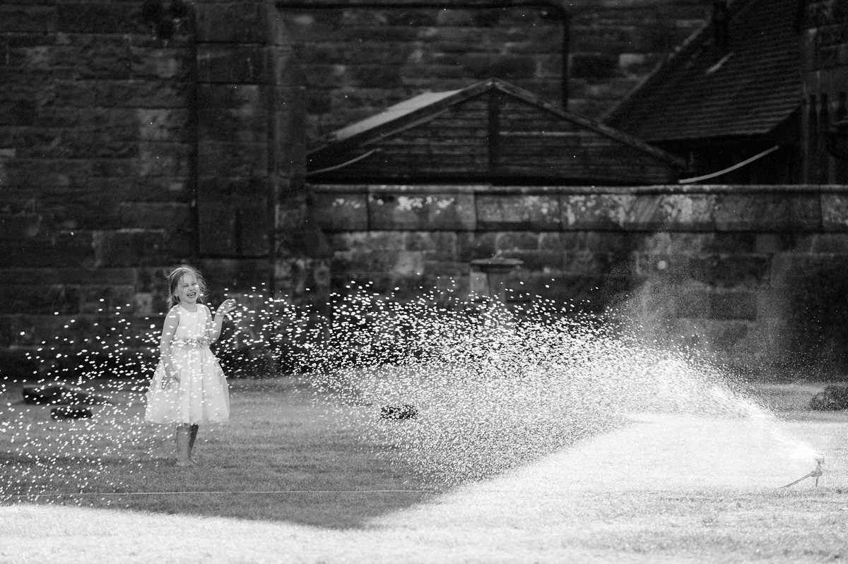 Flower girl playing and having fun with the water sprayer in black and white