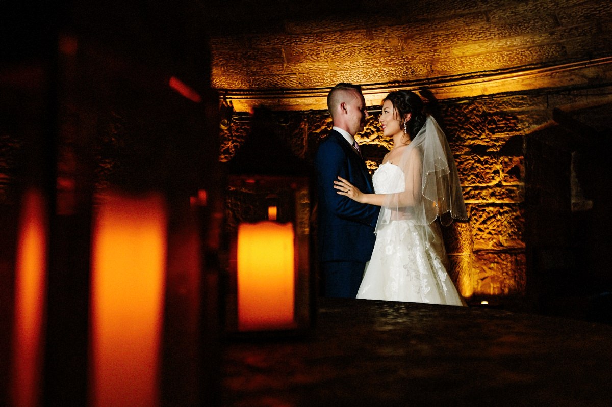 Candles and the bride and groom in the wine cellar at Peckforton Castle