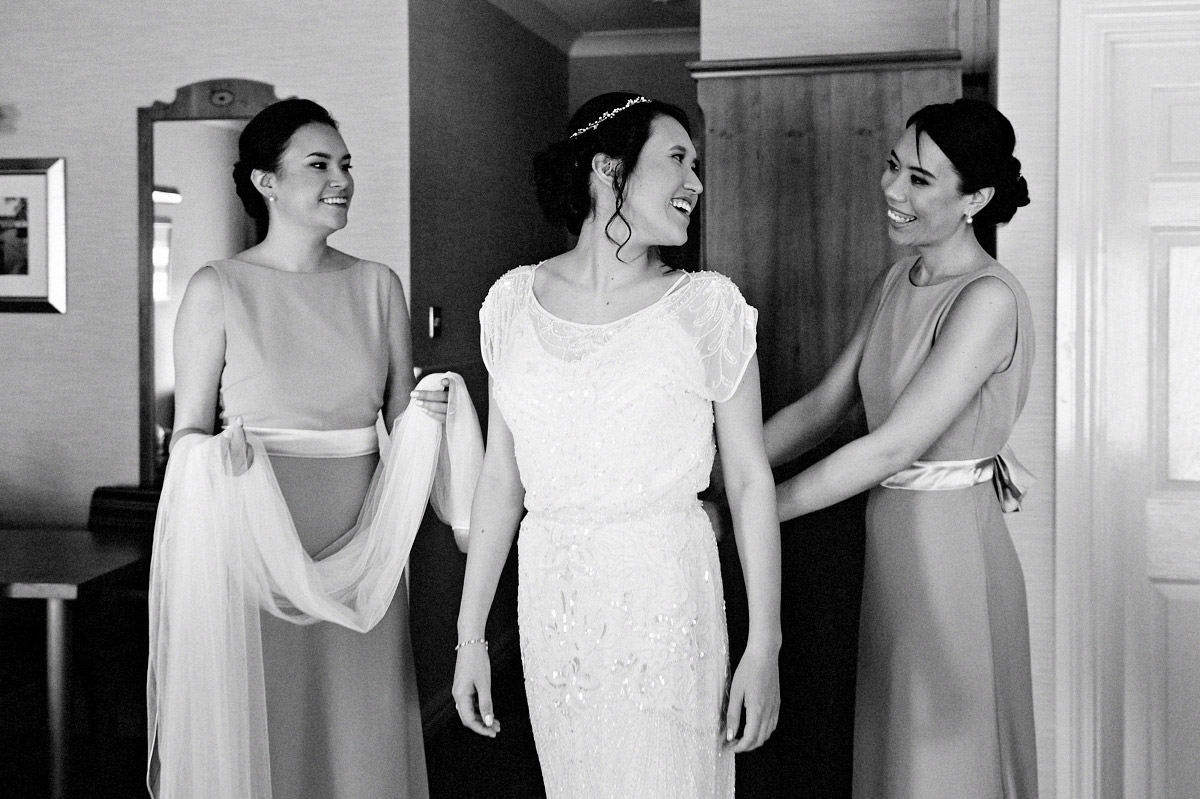 Bridesmaids helping the bride with her wedding dress before the wedding ceremony