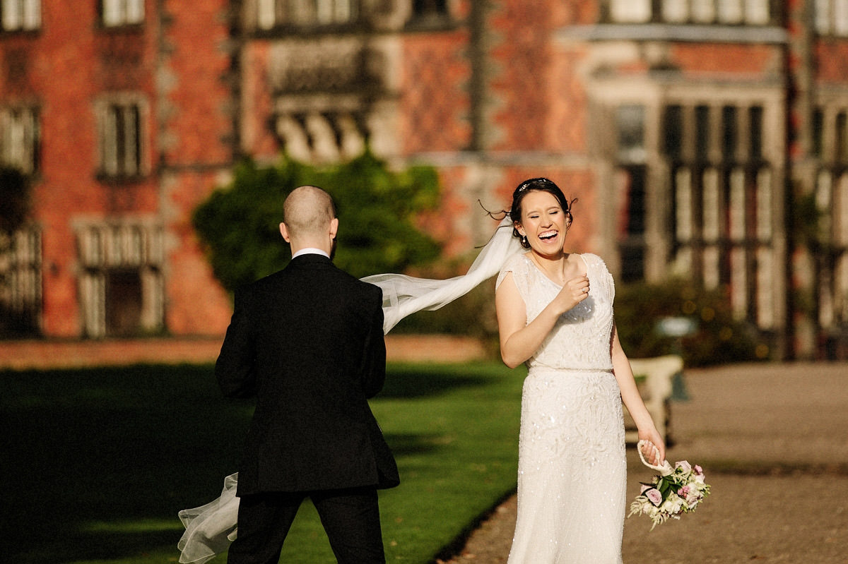 Fun natural moment with the brides veil blowing in the wind and the groom trying to catch it